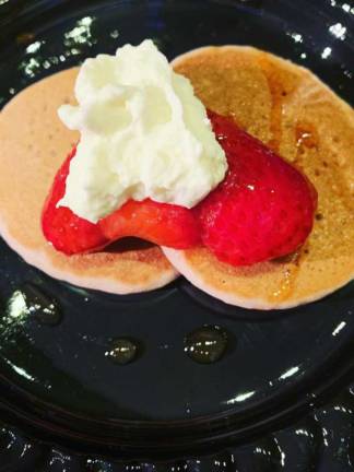 Pancakes with toppings of strawberries and whipped cream